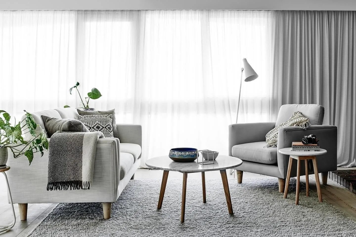 Wide living space with full-height sheer curtains and layered drapes
