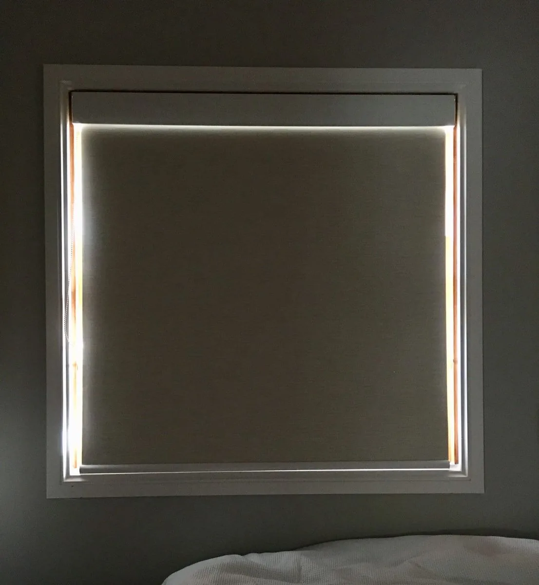 Blockout roller blind fitted inside a bedroom window frame, holding daylight out