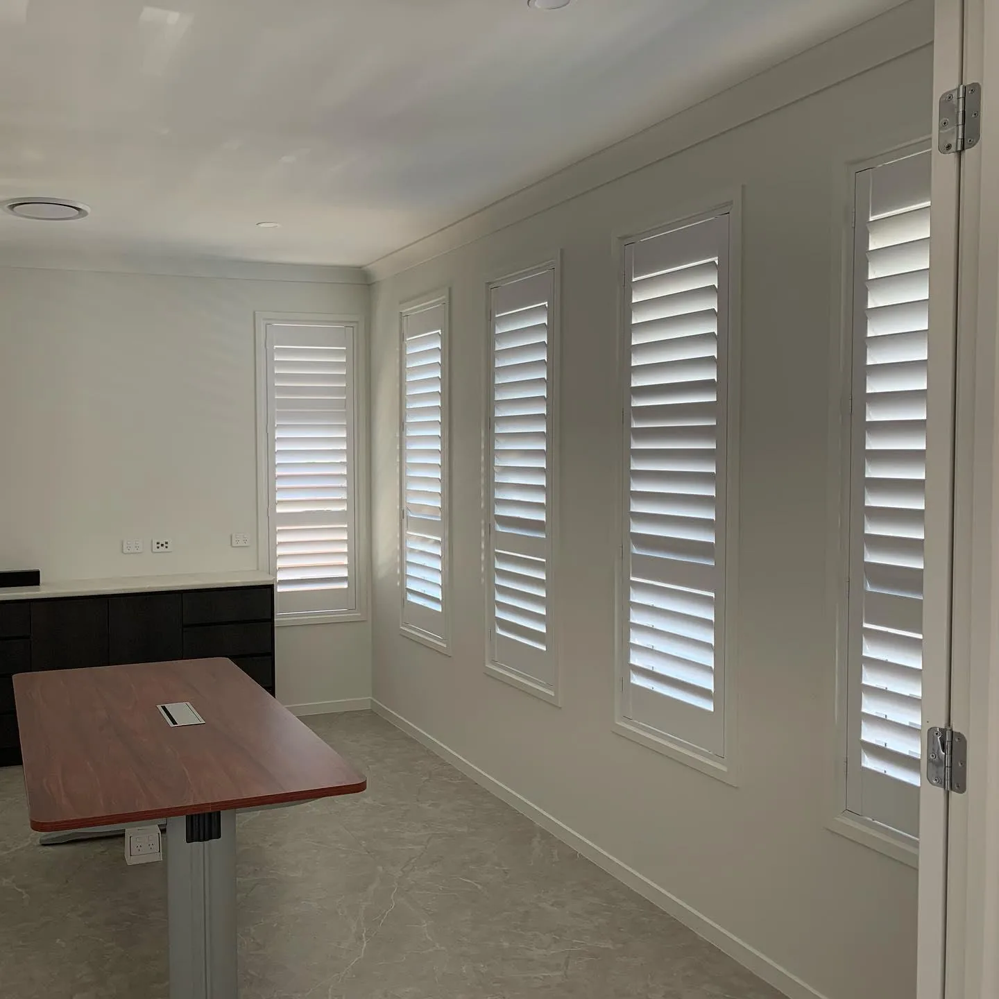 Plantation shutters fitted along a wall of windows in a Brisbane home