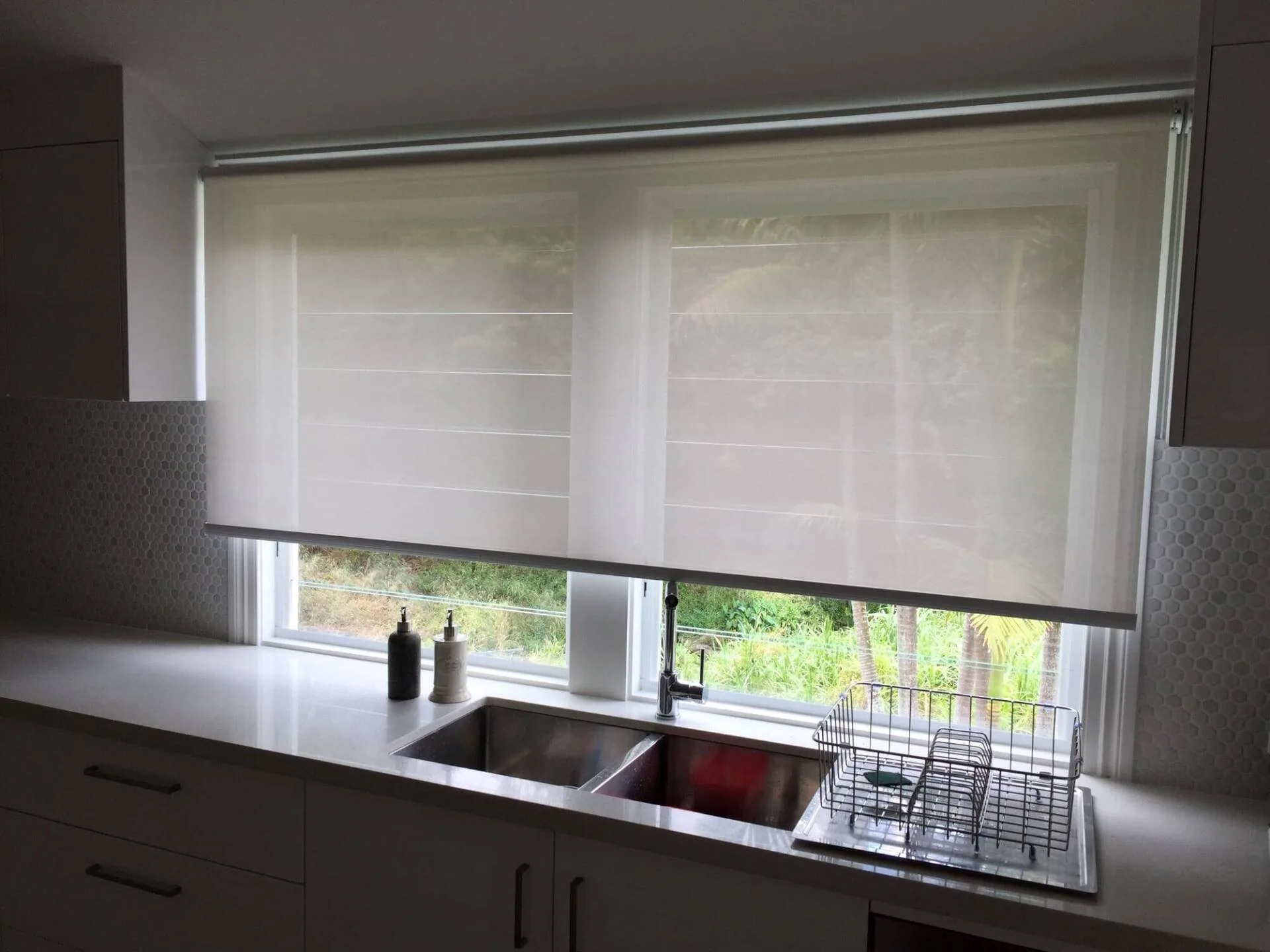 Roller blind lowered over a kitchen window above the sink