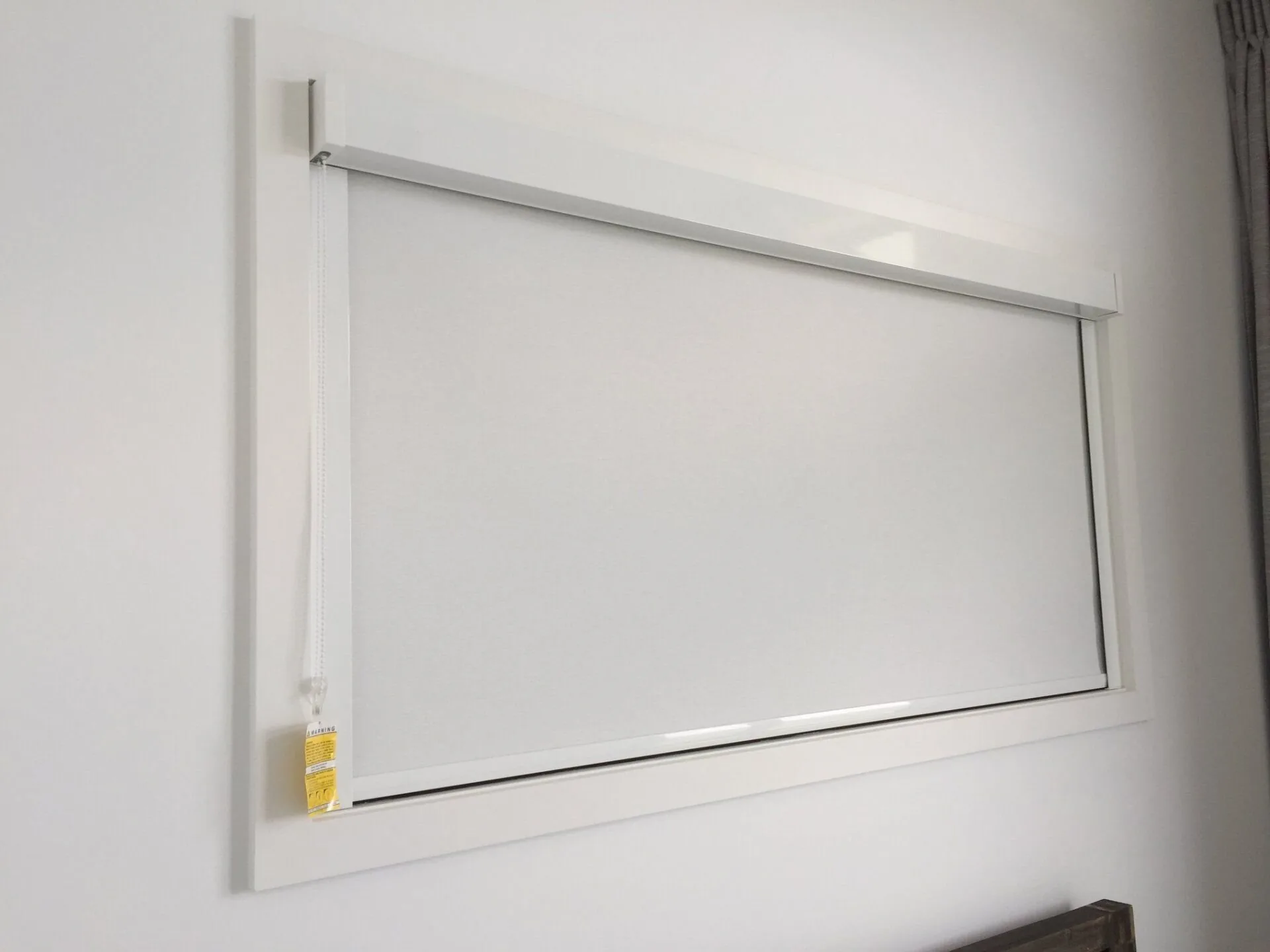 Dark roller blind fitted neatly inside a window frame