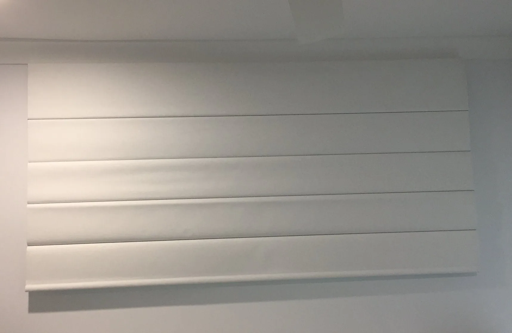Roman blind raised in even horizontal folds at a window