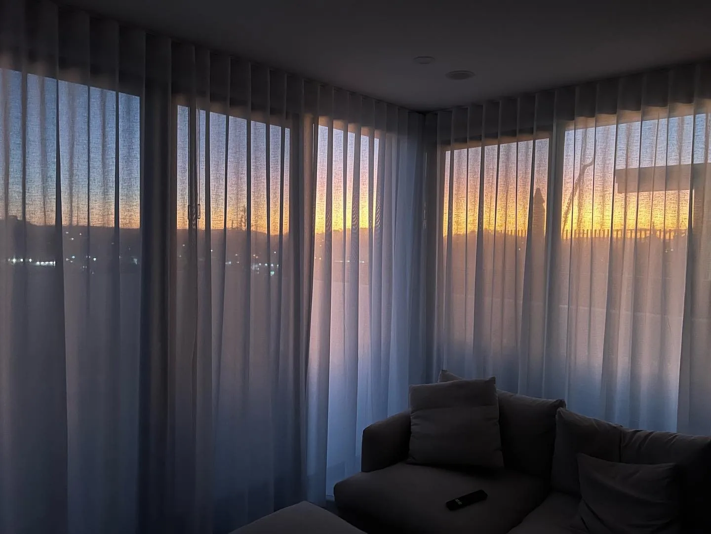 Sheer curtains layered along a wide living room window wall